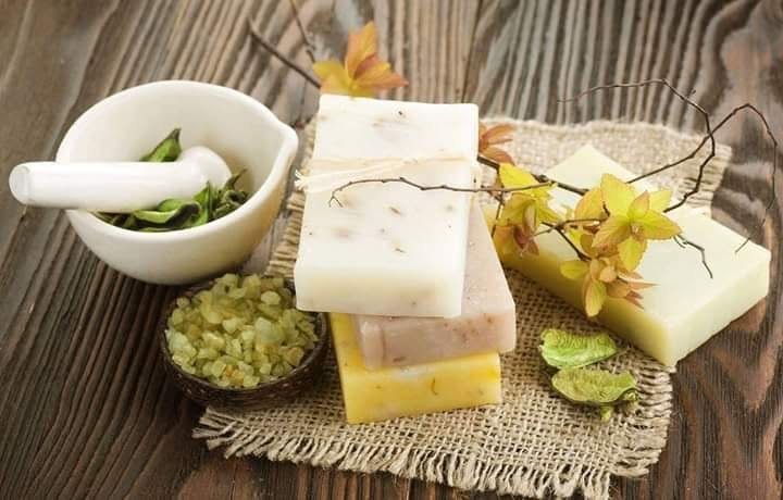 Handmade soap bars beside a mortar and botanical ingredients